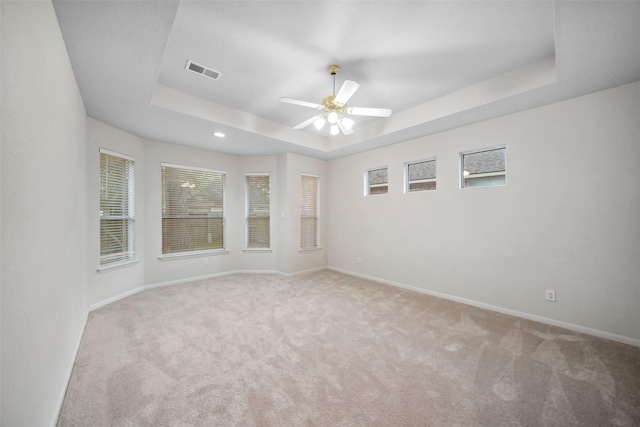 carpeted spare room featuring a raised ceiling and ceiling fan