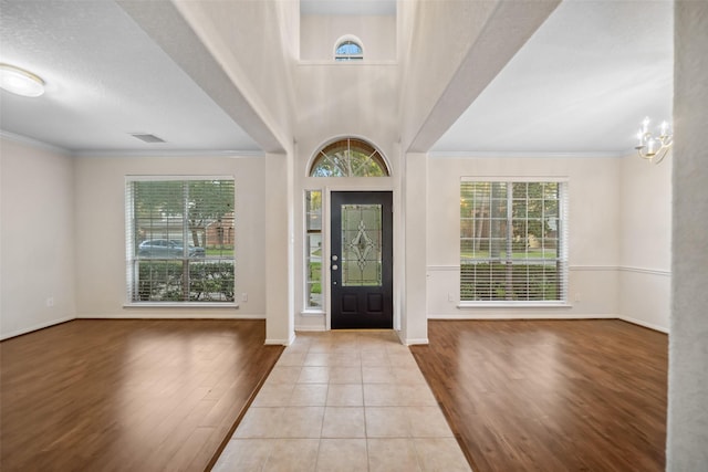 entrance foyer featuring a wealth of natural light, light tile patterned floors, ornamental molding, and an inviting chandelier