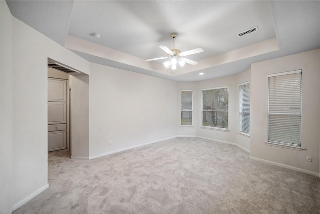 carpeted empty room with a tray ceiling and ceiling fan