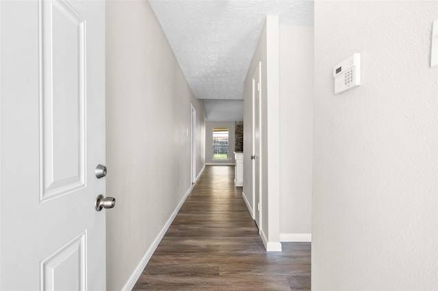 corridor featuring dark hardwood / wood-style flooring and a textured ceiling