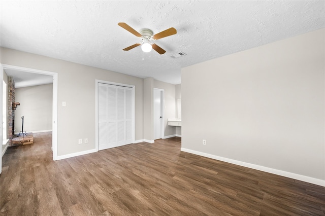 unfurnished bedroom with a fireplace, dark hardwood / wood-style flooring, a textured ceiling, and ceiling fan