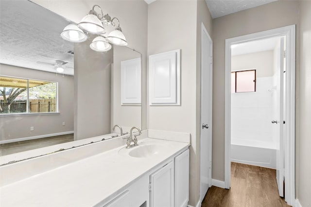 bathroom featuring a textured ceiling, vanity, ceiling fan, shower / bathing tub combination, and hardwood / wood-style flooring