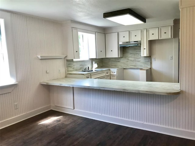 kitchen featuring backsplash, white cabinets, sink, dark hardwood / wood-style floors, and kitchen peninsula