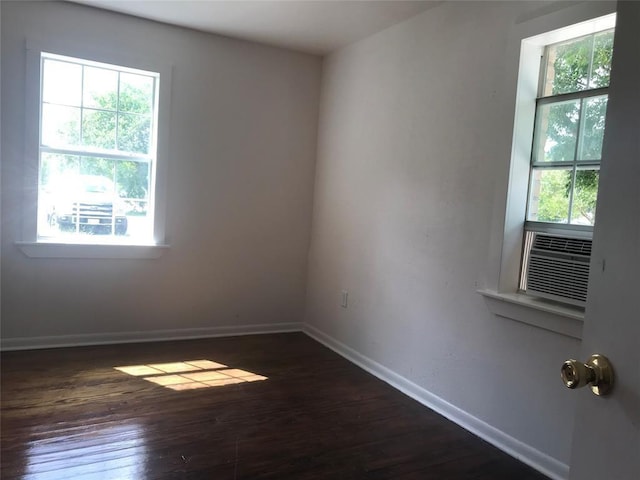 unfurnished room with dark hardwood / wood-style floors, a healthy amount of sunlight, and cooling unit