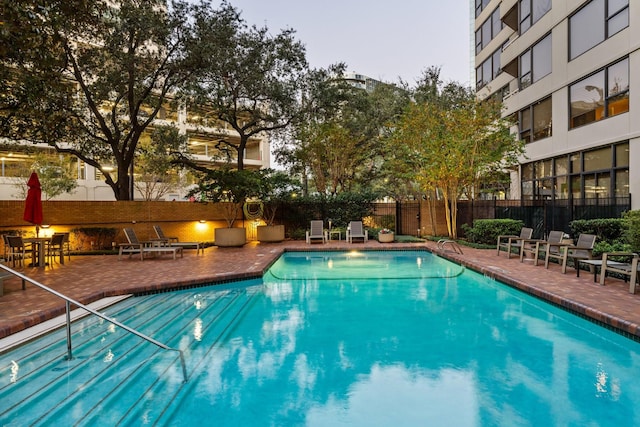 pool at dusk with a patio area