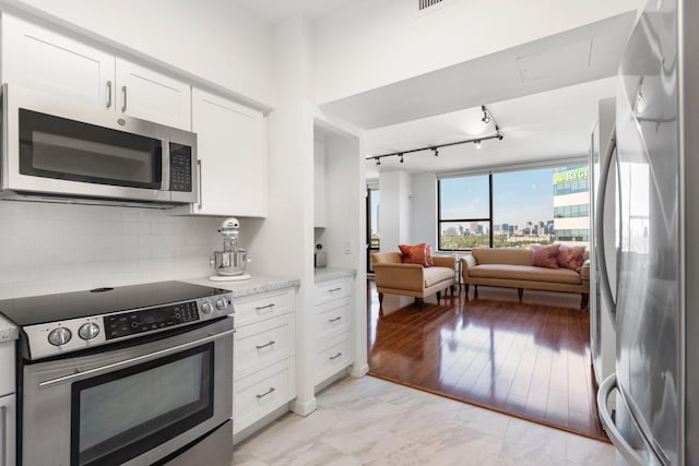 kitchen featuring white cabinets, light stone counters, appliances with stainless steel finishes, and tasteful backsplash