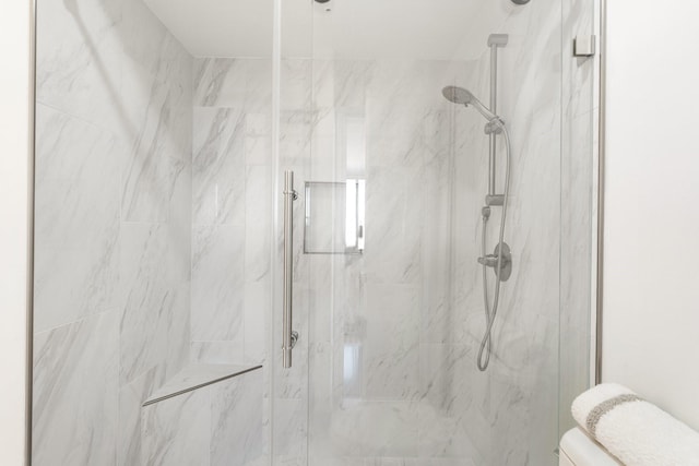 bathroom featuring toilet and a shower with door