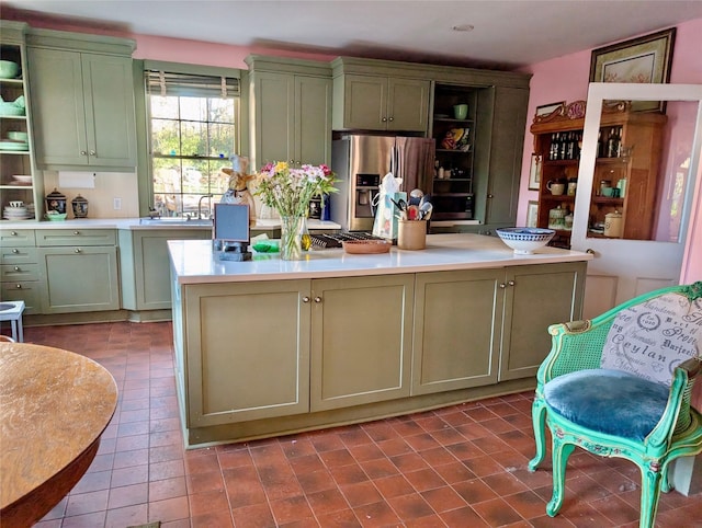 kitchen with green cabinets, a center island, stainless steel refrigerator with ice dispenser, and tile patterned flooring