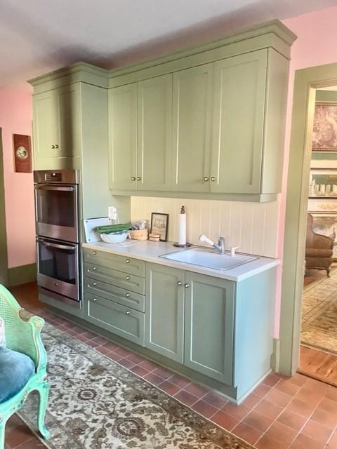 interior space featuring light tile patterned flooring, double oven, green cabinets, and sink