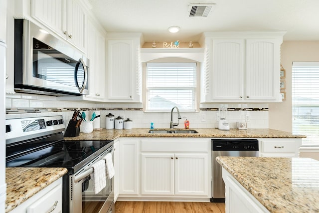 kitchen with light stone counters, sink, white cabinetry, and stainless steel appliances