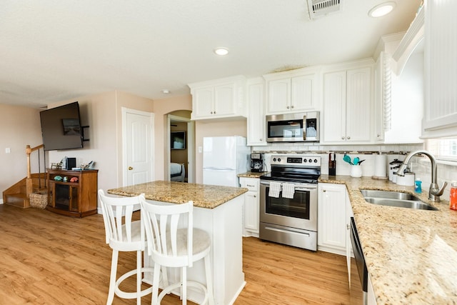 kitchen featuring light stone countertops, stainless steel appliances, white cabinets, and sink