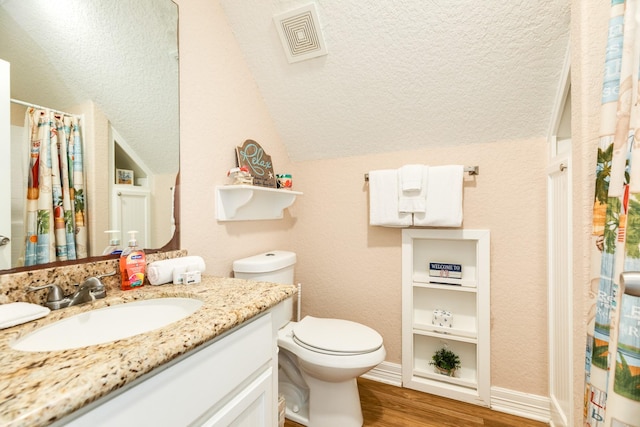 bathroom featuring toilet, vanity, hardwood / wood-style flooring, and vaulted ceiling