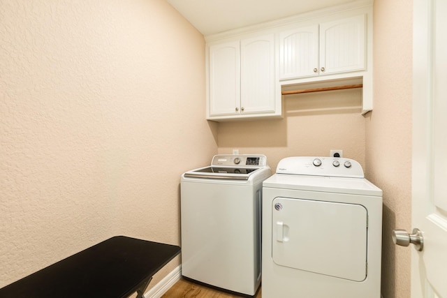 laundry room featuring cabinets, light hardwood / wood-style floors, and washer and clothes dryer