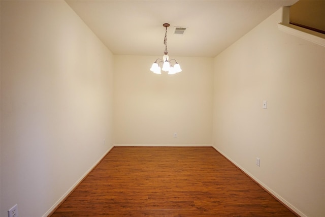 unfurnished room featuring hardwood / wood-style flooring and a chandelier