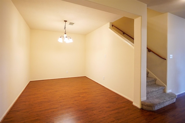 empty room with dark hardwood / wood-style floors and a notable chandelier