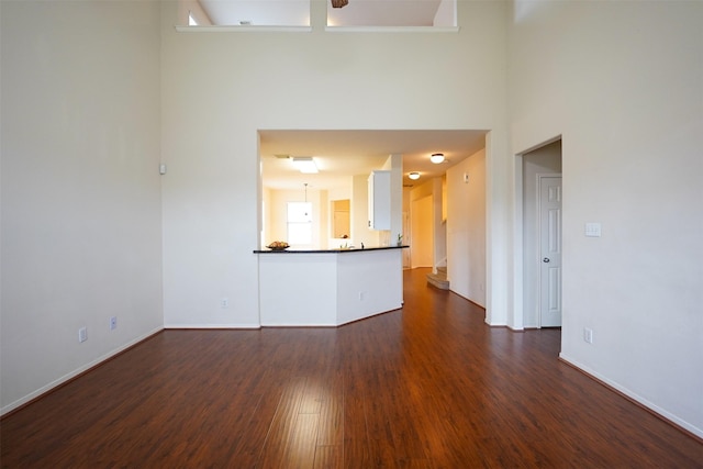 unfurnished living room featuring dark hardwood / wood-style floors and a towering ceiling