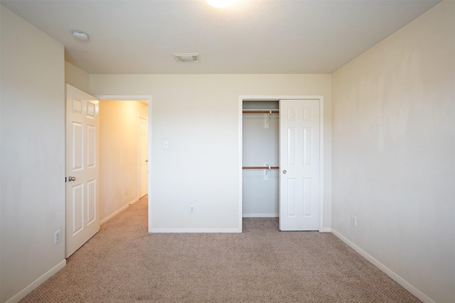 unfurnished bedroom featuring light carpet and a closet