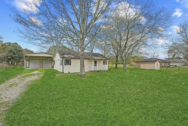 view of front of house featuring a garage, a front lawn, and a storage shed