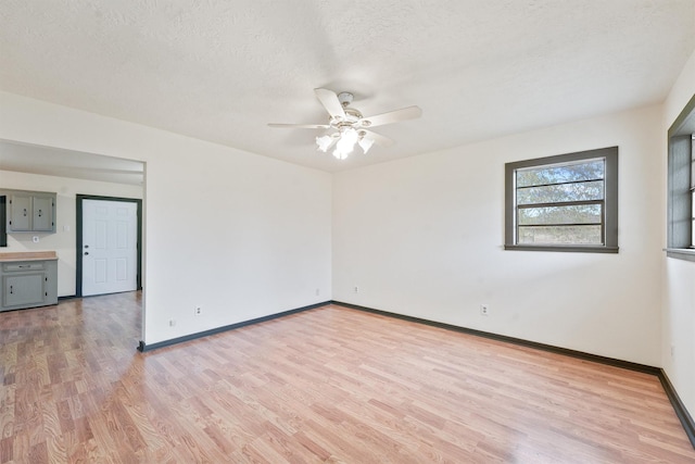 spare room with ceiling fan, a textured ceiling, and light wood-type flooring