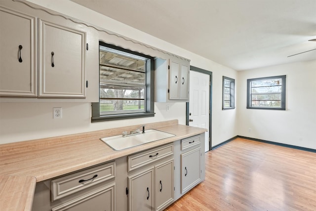 kitchen featuring ceiling fan, sink, gray cabinetry, and light wood-type flooring