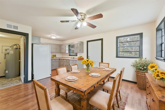 dining space featuring ceiling fan, light hardwood / wood-style flooring, and water heater