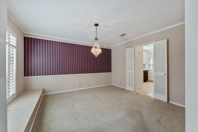 carpeted empty room featuring crown molding and an inviting chandelier