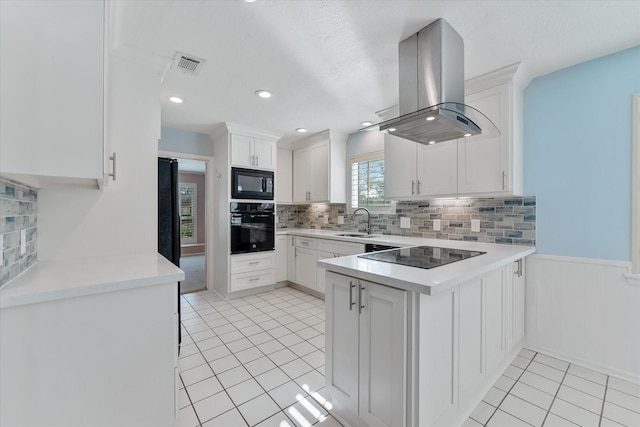 kitchen featuring sink, island range hood, white cabinetry, and black appliances