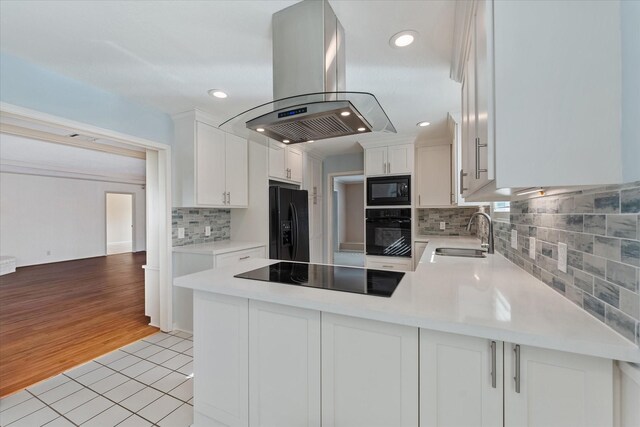 kitchen with sink, white cabinets, island exhaust hood, light tile patterned floors, and black appliances