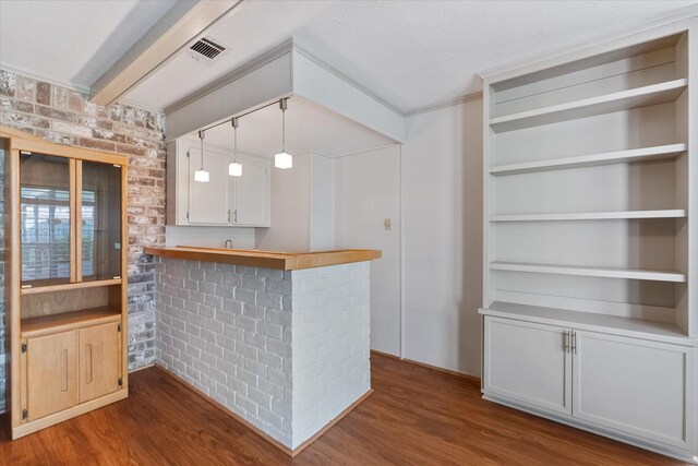 bar featuring white cabinetry, brick wall, dark wood-type flooring, and decorative light fixtures