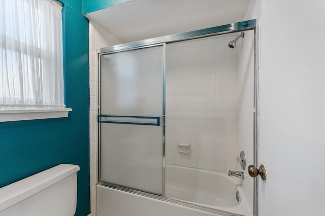 bathroom with toilet and combined bath / shower with glass door