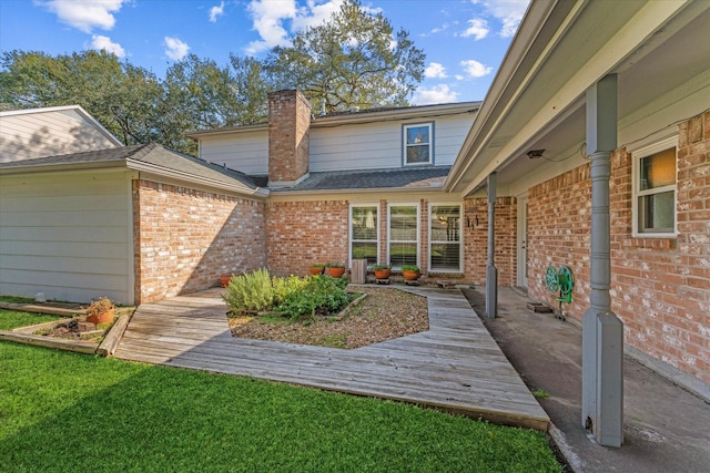 property entrance with a wooden deck and a lawn