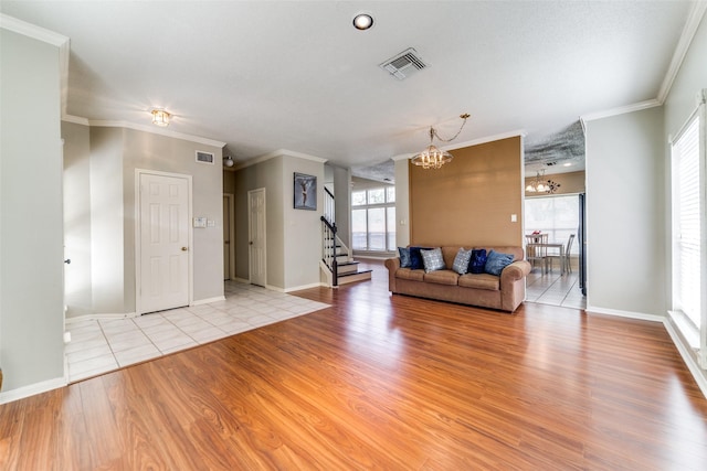 unfurnished living room featuring a chandelier, light wood-type flooring, and ornamental molding