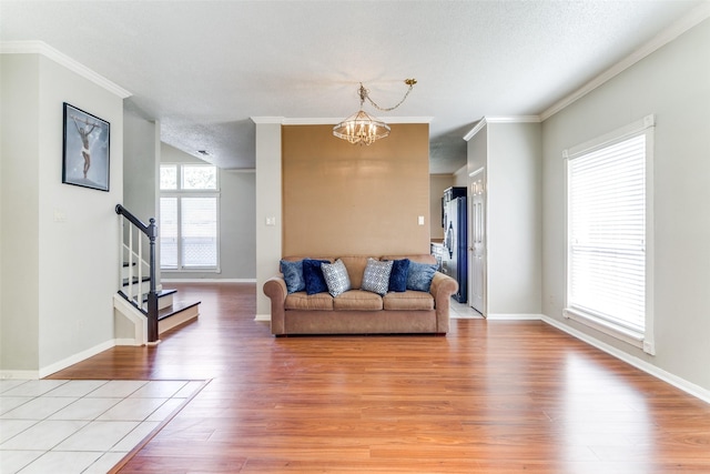 living room with a notable chandelier, a healthy amount of sunlight, and ornamental molding