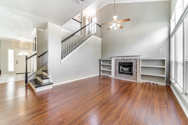 unfurnished living room featuring a high ceiling, a textured ceiling, ceiling fan, and hardwood / wood-style floors