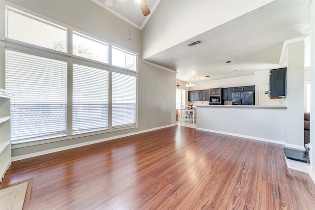 unfurnished living room with ceiling fan with notable chandelier, dark hardwood / wood-style floors, and ornamental molding