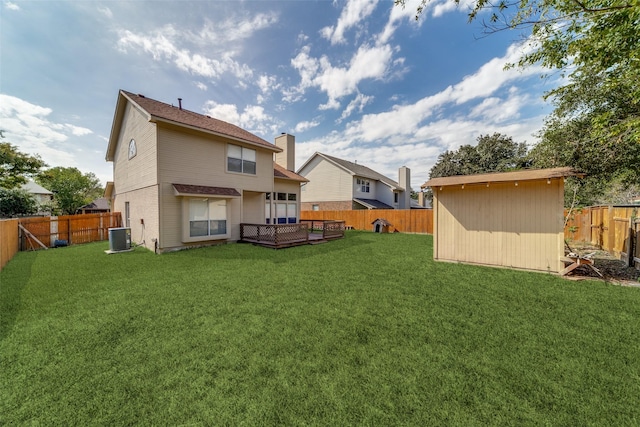 rear view of property with a yard, central AC unit, and a storage shed