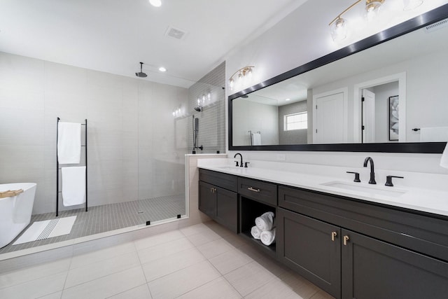 bathroom with a tile shower, vanity, and tile patterned floors