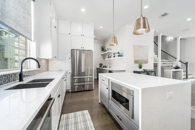 kitchen featuring pendant lighting, a center island, white cabinets, sink, and stainless steel appliances