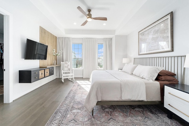 bedroom with ceiling fan, dark hardwood / wood-style floors, and a tray ceiling