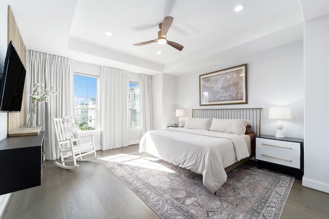 bedroom with wood-type flooring, a raised ceiling, and ceiling fan