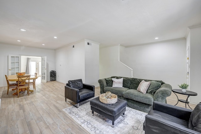 living room featuring french doors, crown molding, and light hardwood / wood-style flooring