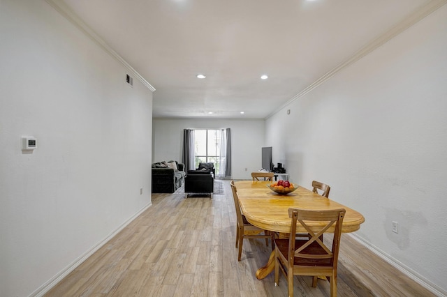 dining space featuring ornamental molding and light hardwood / wood-style flooring