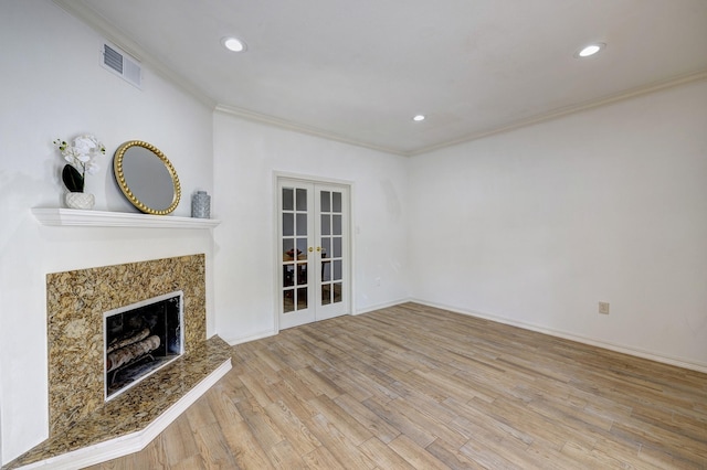 unfurnished living room with crown molding, a high end fireplace, light hardwood / wood-style floors, and french doors