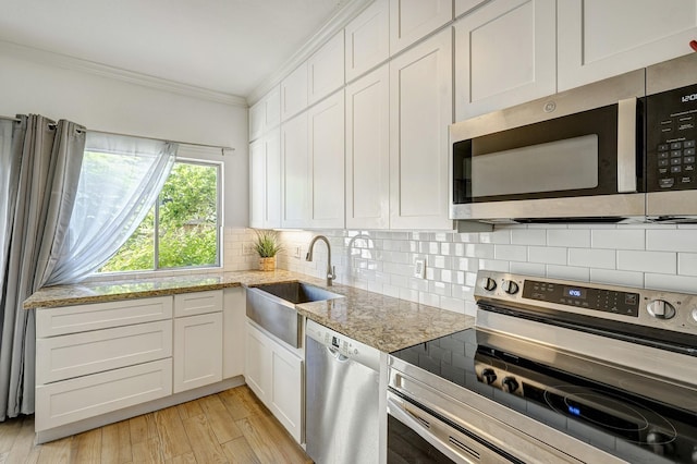 kitchen with light stone counters, sink, stainless steel appliances, and white cabinets