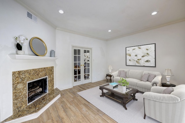 living room with french doors, crown molding, and light hardwood / wood-style flooring