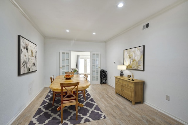 dining space with crown molding, light hardwood / wood-style flooring, and french doors