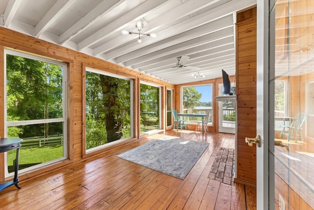 unfurnished sunroom featuring vaulted ceiling with beams, ceiling fan with notable chandelier, and a healthy amount of sunlight