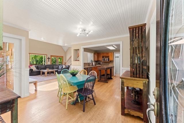 dining room featuring light wood-type flooring, crown molding, and sink