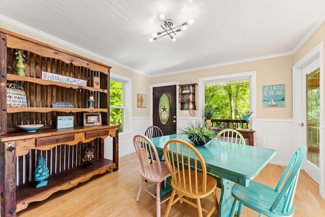 dining area with ornamental molding and light hardwood / wood-style flooring