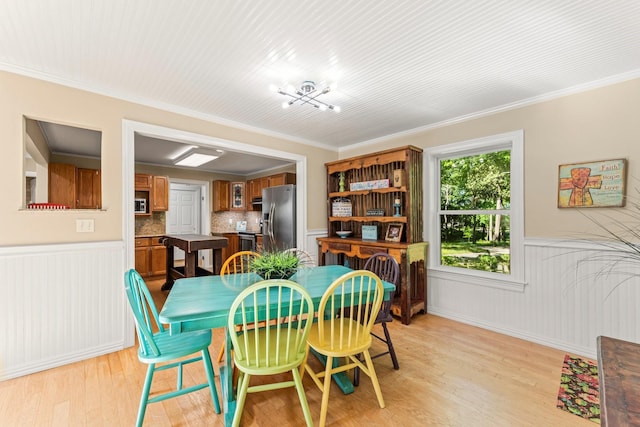 dining room with light wood-type flooring and ornamental molding